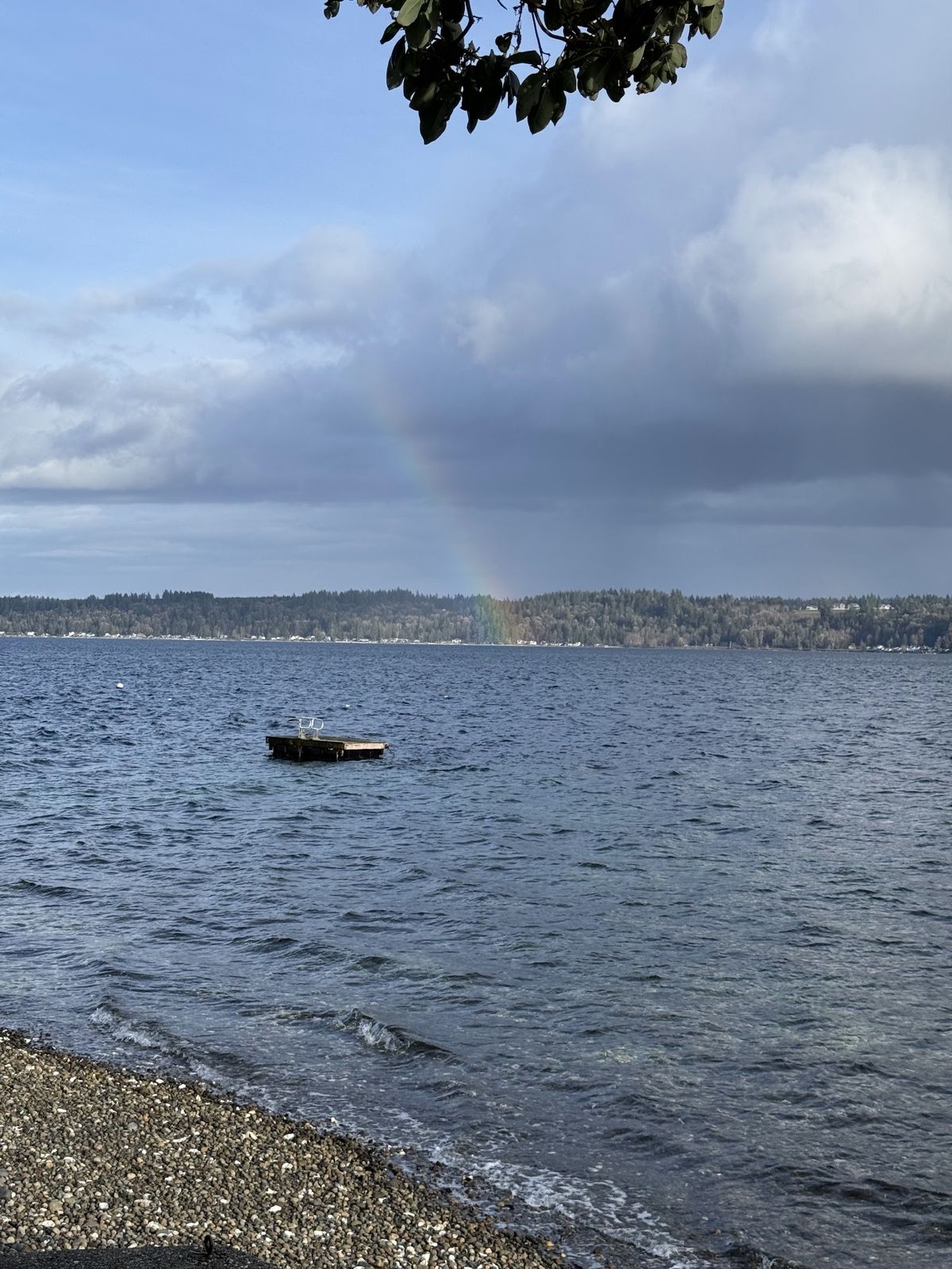 Rainbow over Hood Canal with dock in the water and pebble shoreline